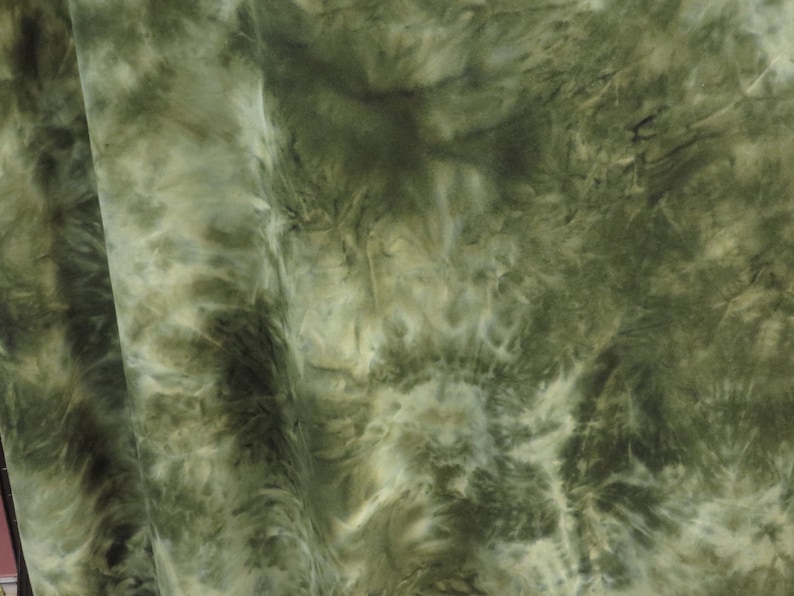 Puede incluir: Primer plano de una tela con un estampado tie-dye en tonos verdes y blancos. La tela tiene un aspecto suave y fluido, con los colores mezcl&aacute;ndose en un dise&ntilde;o arremolinado. La tela se utiliza probablemente para ropa o decoraci&oacute;n del hogar.