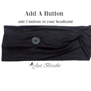 May include: Black headband with a single black button in the center. The headband is made of a soft, stretchy fabric. The text "Add A Button" and "add 2 buttons to your headband" is above the headband. The text "Just Breathe" is below the headband.