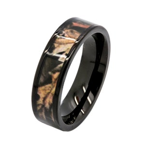 May include: A black tungsten carbide ring with a camouflage pattern inlay. The ring has a polished finish and a comfortable fit.