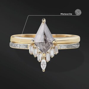Pode incluir: Um conjunto de an&eacute;is de duas pe&ccedil;as com uma banda de ouro e uma banda de meteorito. O anel de noivado tem uma pedra grande, cinzenta, em forma de pipa com pedras menores de corte baguette e uma pedra em forma de marquesa. A palavra "Meteorite" est&aacute; na imagem.