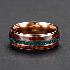 May include: A rose gold band with a wooden inlay and a green opal accent. The ring is a unique and stylish piece of jewelry.