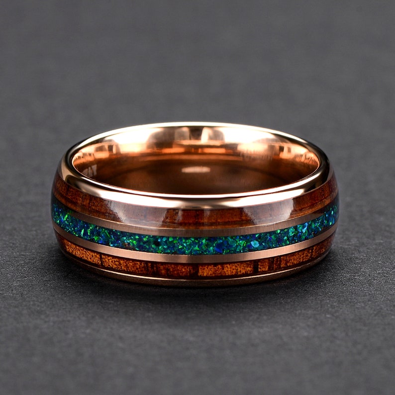 May include: A rose gold band with a wooden inlay and a green opal accent. The ring is a unique and stylish piece of jewelry.
