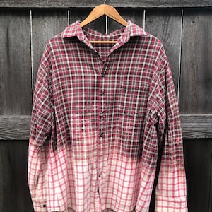 May include: A red and black plaid flannel shirt with a bleached bottom half. The shirt is faded and has a distressed look.