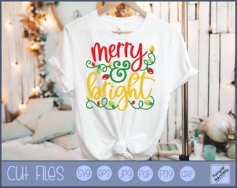 Peut inclure: T-shirt blanc avec le texte "merry & bright" en lettres rouges, jaunes et vertes avec un motif de guirlande lumineuse.