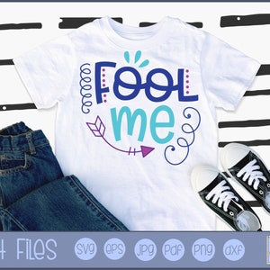 Puede incluir: Una camiseta blanca con el texto "Fool me" en letras azules, turquesa y moradas. El texto está rodeado de espirales y una flecha. La camiseta está sobre un fondo blanco con rayas negras y blancas.