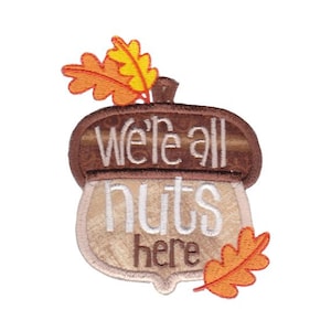 May include: Embroidered acorn-shaped patch with the text "We're all nuts here" and two orange and yellow leaves.