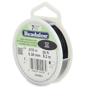 May include: A spool of black Beadalon 7-strand bead stringing wire. The label indicates a diameter of .015 inches and a length of 30 feet. The packaging features a white plastic spool with a hanging tab, a barcode, and product specifications.