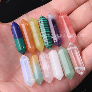 May include: A collection of 12 gemstone point beads, each with a hole drilled through the top. The beads are in various colours, including clear, green, pink, orange, yellow, purple, and blue.  Amazingbead.Etsy.com