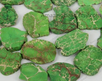 May include: A strand of green and brown jasper gemstone beads. The beads are irregularly shaped and have a mottled appearance. The beads are strung on a clear thread.