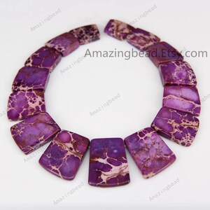 Pu&ograve; includere: Una collana di perline di pietre preziose con motivi viola e bianchi. Le perline sono rettangolari e hanno una forma leggermente curva. Le perline sono infilate su uno spago trasparente e sono pronte per essere utilizzate per la creazione di gioielli.
