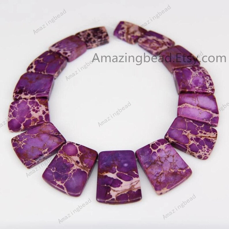 Pu&ograve; includere: Una collana di perline di pietre preziose con motivi viola e bianchi. Le perline sono rettangolari e hanno una forma leggermente curva. Le perline sono infilate su uno spago trasparente e sono pronte per essere utilizzate per la creazione di gioielli.