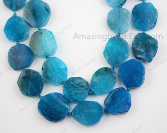 May include: A strand of blue agate gemstone beads, each bead is a unique, irregular shape with a light blue to dark blue color gradient. The beads are strung on a thin cord and are ready for jewelry making.