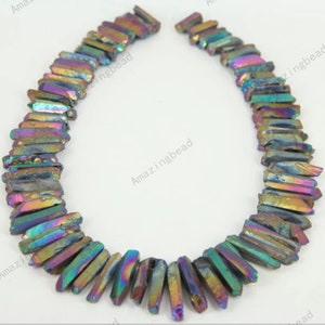 Può includere: Una collana di perline di cristallo iridescenti color arcobaleno. Le perline sono sfaccettate e hanno una forma appuntita. Le perline sono infilate su uno spago trasparente.