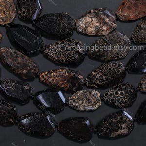 Könnte beinhalten: Nahaufnahme einer Kette aus schwarzen und braunen Edelsteinperlen. Die Perlen haben eine Mischung aus facettierten und strukturierten Oberflächen mit komplizierten Mustern. Der Text "Amazingbead.etsy.com" ist auf einigen Perlen sichtbar. Die Perlen sind auf einer schwarzen Schnur aufgefädelt.