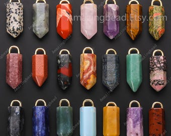 May include: A selection of gemstone pendants in diverse colours and patterns, such as red, pink, purple, and green. Each pendant features a gold-coloured loop at the top for attaching to a chain or cord. The pendants are shown against a black backdrop.