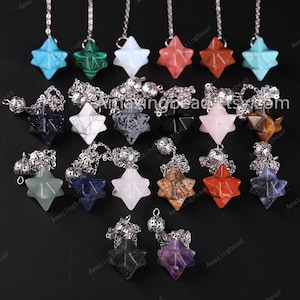 May include: A collection of 18 star-shaped crystal pendulums with silver chains and a silver ball at the end. The crystals are in various colors, including blue, green, pink, red, white, black, and brown.