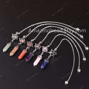 May include: Seven silver star of David pendants with different colored crystal points hanging from silver chains. The crystals are green, orange, red, purple, pink, and blue.