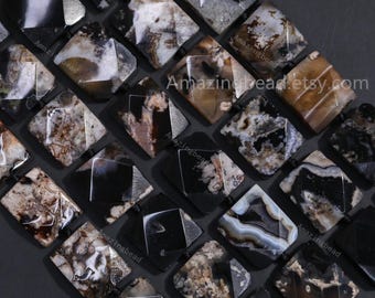 May include: Close-up of a collection of gemstone beads. The beads are a mix of black, white, and brown with unique patterns. The beads are rectangular with beveled edges and strung together. The text "Amazingbead.etsy.com" is visible.