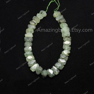 May include: A strand of light green faceted gemstone beads. The beads are irregularly shaped and have a slightly translucent appearance. The beads are strung on a green thread.