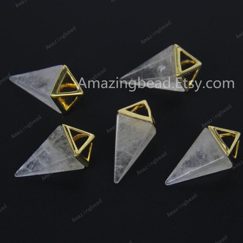 K&ouml;nnte beinhalten: F&uuml;nf klare Quarzkristall-Pyramidenanh&auml;nger mit goldfarbenen Metallkappen. Die Anh&auml;nger sind etwa 2,5 cm lang.