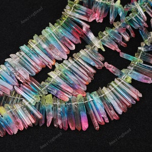 May include: A strand of iridescent rainbow crystal points, also known as angel aura quartz, with a pointed tip and a flat back. The crystals are strung on a clear thread and are approximately 1-2 inches in length.