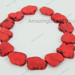 Puede incluir: Una hebra de cuentas de piedra natural de color rojo, de forma irregular. Las cuentas son de diferentes tamaños y formas, pero todas son de un color rojo intenso con vetas blancas que las atraviesan. Las cuentas están enhebradas en un hilo transparente y están listas para ser utilizadas en la elaboración de joyas.