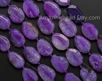 May include: Close-up of strands of purple agate gemstone beads. The beads are oval-shaped with a faceted cut, showcasing a range of purple hues and natural patterns. The text "Amazingbead.Etsy.com" is visible.