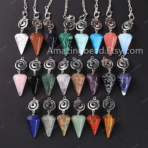 Könnte beinhalten: Eine Sammlung von 18 Kristallspitzenpendeln mit silbernen Spiralen. Die Kristalle sind in verschiedenen Farben, darunter rosa, schwarz, grün, weiß, braun, lila, grau, blau und rot.