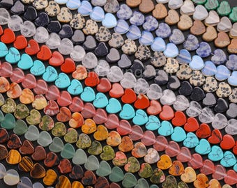 May include: Assortment of heart-shaped gemstone beads in various colors, including red, green, blue, brown, and white. The beads are arranged in rows, creating a colorful and textured pattern.