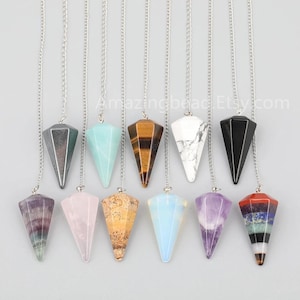 May include: A set of 10 crystal pendulums with silver chains. The pendulums are made of various crystals, including amethyst, rose quartz, tiger's eye, and clear quartz.