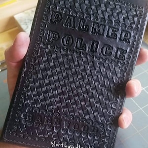 May include: Black leather wallet with "PALMER POLICE" embossed on the front. The wallet has a checkered pattern and the text "NORTHWINDLEATHER.COM" is printed on the bottom.