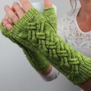 Könnte beinhalten: Grüne gestrickte Fingerlose Handschuhe mit einem geflochtenen Muster.