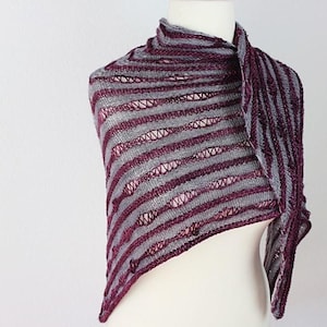 May include: A gray and burgundy striped shawl with a lacy pattern. The shawl is draped over a white mannequin.