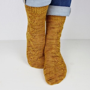 Könnte beinhalten: Senfgelbe Strickstrümpfe mit Zopfmuster. Die Socken werden mit blauen Jeans getragen. Die Socken sind aus einem weichen, warmen Material gefertigt, ideal für kaltes Wetter. Die Socken sind ein gemütliches und stilvolles Accessoire.