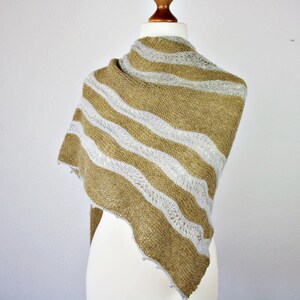 May include: A brown and white striped knitted shawl with a lacy pattern. The shawl is draped over a white mannequin.