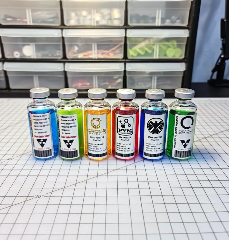 May include: Seven small glass bottles with colorful liquids and labels. The labels have different logos and text, including "Pym Particles", "Cross Technologies", and "Oscorp".