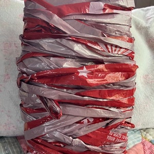 May include: A tightly wound roll of red and silver plastic ribbon. The red ribbon has white stars and text that reads "10 Ways to Your Target". The cardboard top has the number "40.8" written on it.