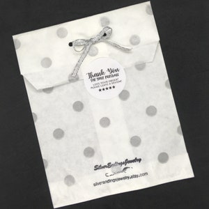 May include: A white paper bag with silver polka dots and a thank you sticker that says "Thank You for your purchase. Love your order? Please leave a review!" with five stars. The bag is tied with a silver ribbon. The bottom of the bag has a black and white logo that says "Silver Endings Jewelry" and "silverendingsjewelry.etsy.com".