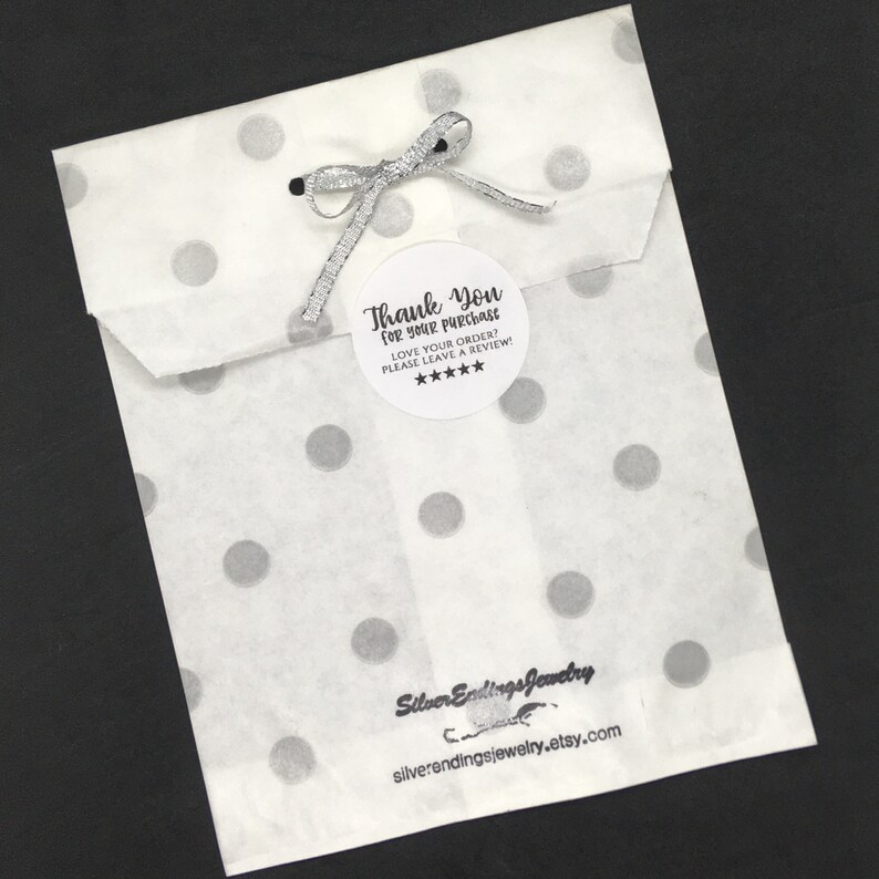 May include: A white paper bag with silver polka dots and a thank you sticker that says "Thank You for your purchase. Love your order? Please leave a review!" with five stars. The bag is tied with a silver ribbon. The bottom of the bag has a black and white logo that says "Silver Endings Jewelry" and "silverendingsjewelry.etsy.com".