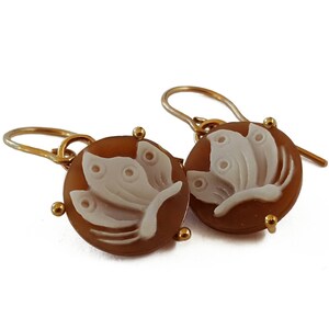 May include: A pair of gold earrings with a cameo butterfly design. The butterfly is carved in white against a brown background.