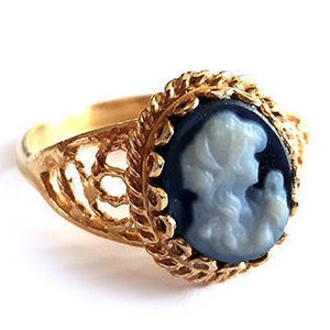 Peut inclure: Bague en or avec un camée noir et blanc représentant le profil d'une femme. La bague est ornée d'un délicat motif de filigrane.