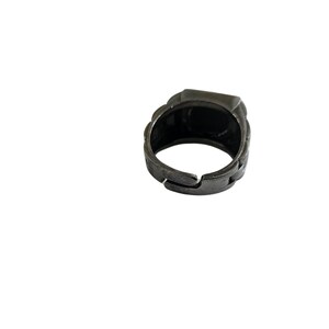 K&ouml;nnte beinhalten: Ein silberfarbener Ring mit quadratischer Oberfl&auml;che. Der Ring ist aus Metall und hat ein strukturiertes Design.