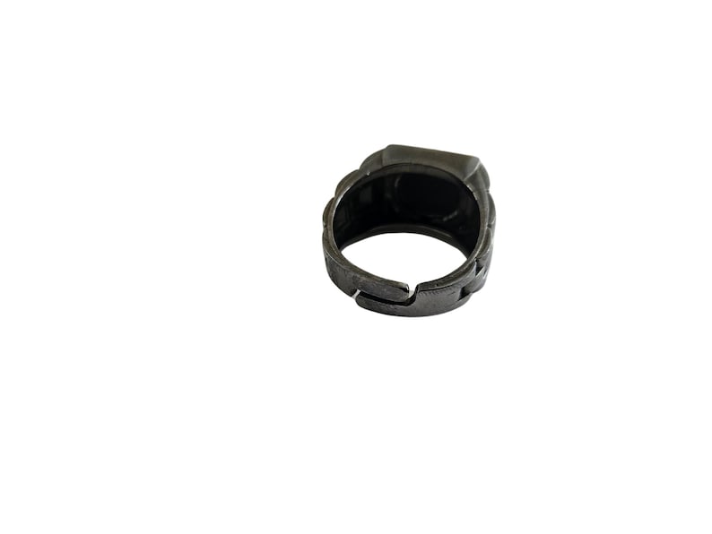 K&ouml;nnte beinhalten: Ein silberfarbener Ring mit quadratischer Oberfl&auml;che. Der Ring ist aus Metall und hat ein strukturiertes Design.