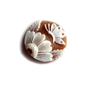May include: A round, brown button with a white carved design of a flower and butterfly.