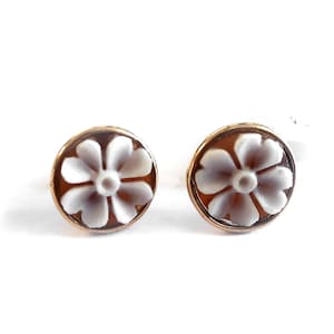 May include: A pair of gold-toned earrings with white cameo flower designs.