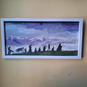 May include: A framed painting showing a landscape with silhouetted figures. The artwork features a purple and blue sky, green ground, and a white frame. The figures appear to be walking across the landscape.