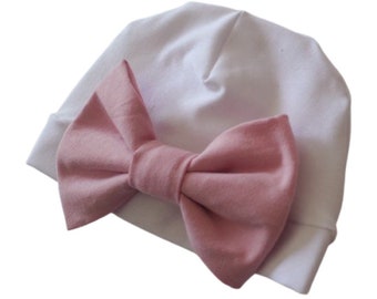 May include: A white beanie with a large pink bow attached to the front.