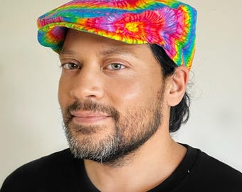Puede incluir: Gorra plana teñida con un diseño de arcoíris. La gorra la lleva una persona con una camiseta negra. El texto "Bazzybears" está en la esquina superior izquierda.