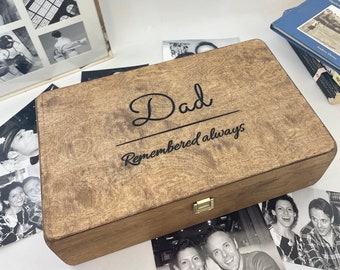 Puede incluir: Una caja de madera con tapa con bisagras y cierre de latón. La caja está teñida de un color marrón oscuro y tiene las palabras "Dad remembered always" grabadas en la parte superior.
