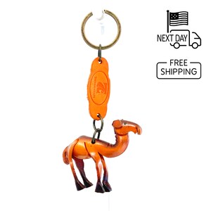 May include: A brown leather camel keychain with a metal ring and a leather tag that says "The Leather Craft".
